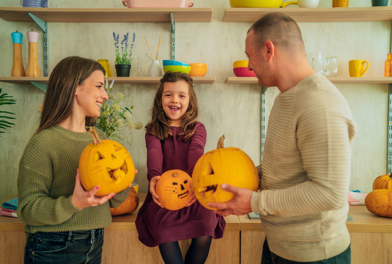 Image is of a young child sitting between her mother and father, concept of co-parenting on Halloween