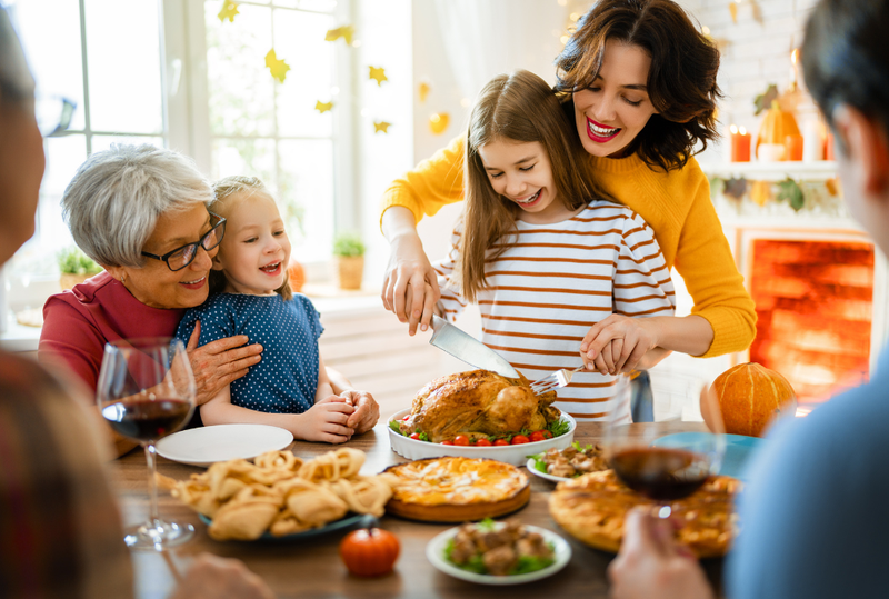 Image is of a mother helping her daughter cut into a cooked turkey, concept of child custody and Thanksgiving holiday schedule