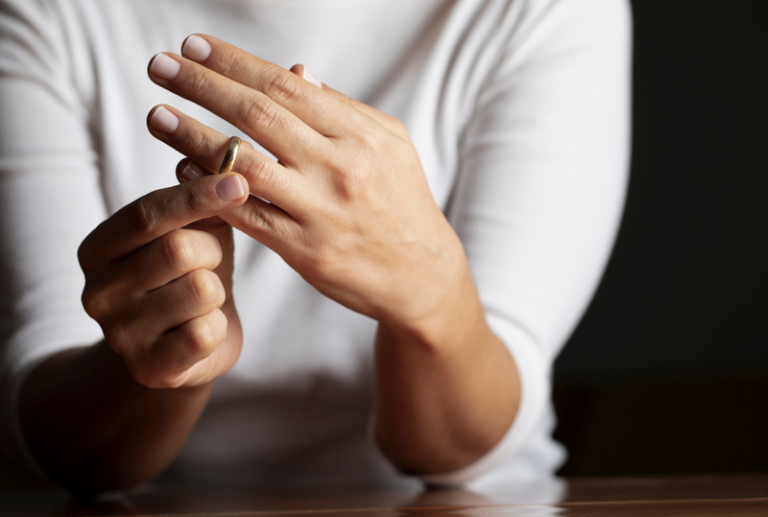 Image is of a closeup of a woman's hands as she taking off her wedding ring, concept of divorce process in Tennessee