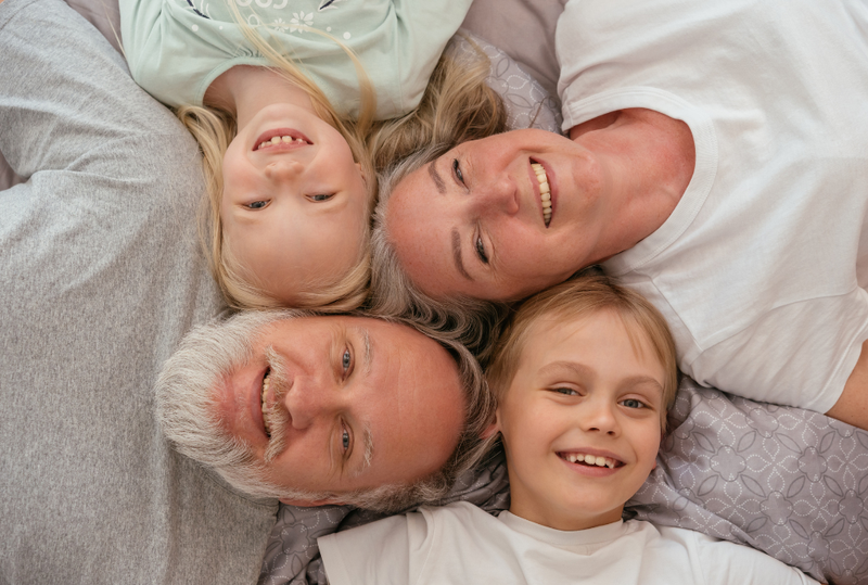 Image is of a grandmother and grandfather and their two granddaughters all laying head to head, concept of how grandparents can file for custody or visitation rights