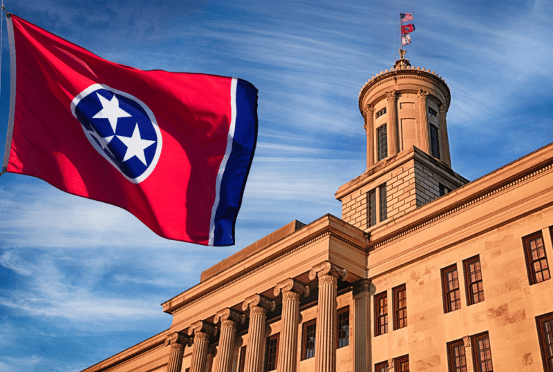 Image is of an exterior view of the Tennessee capitol building with the flag of Tennessee, concept of changes to Tennessee Family Law made in 2024