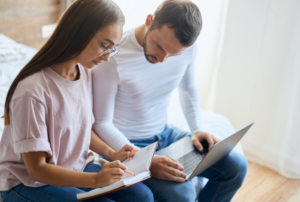 Image is of a mother and father sitting together looking at paperwork and a laptop, concept of a parenting plan for Tennessee parents