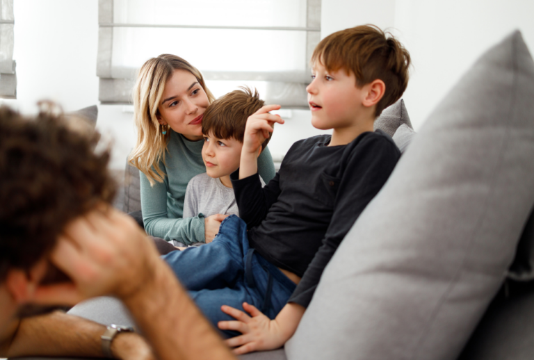 Image is of parents talking to young children while sitting on a couch, concept of how to tell kids about a divorce