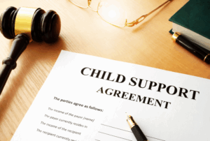 Image is of a paper form that reads 'child support agreement' on a table next to a pen and a judge's gavel, concept of what happens if you don't pay child support in Franklin, Tennessee