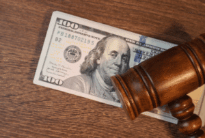 Image is of a judge's gavel laying on top of a stack of hundred dollar bills, concept of how cohabitation can affect alimony in Franklin