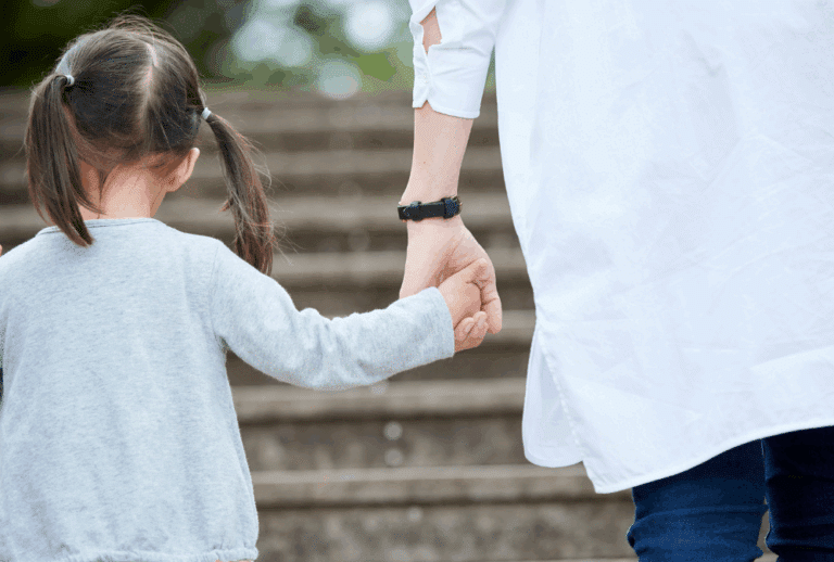 Image is of a mother holding hands with her young daughter while walking up steps, concept of ex is not paying child support in Franklin
