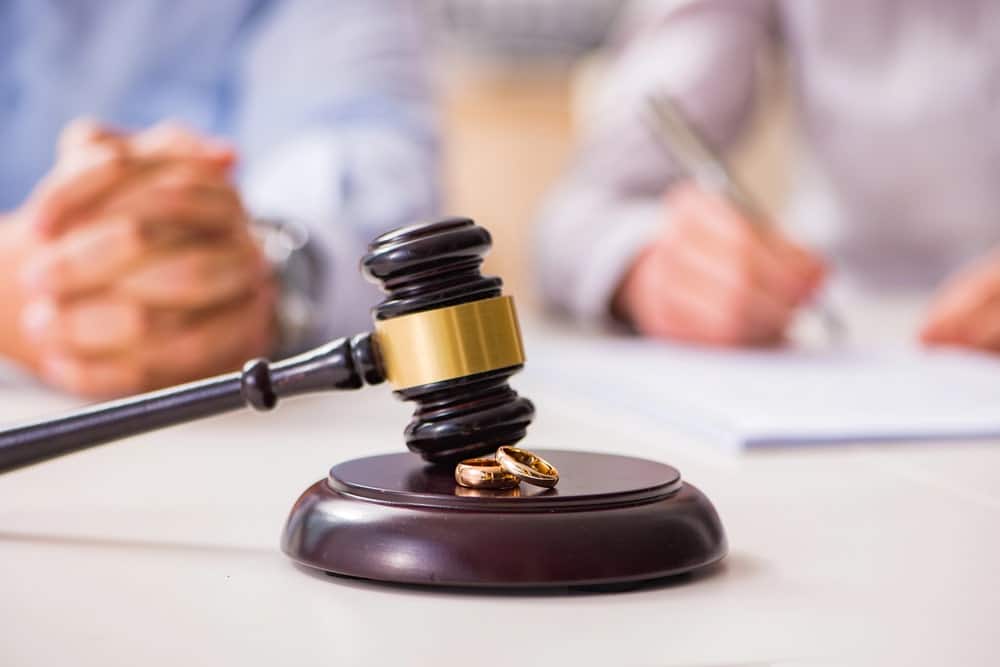 Judge’s gavel with wedding rings on desk during divorce proceedings.