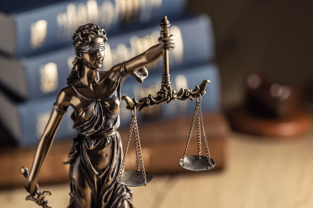 Image is of a Lady Justice statue with balance scales beside law books, concept of legal rights in matters involving child custody and unmarried parents.