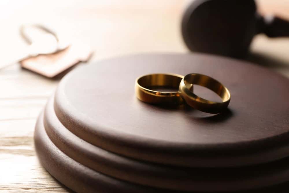 Image shows two wedding rings placed on a judge’s gavel block, concept of court involvement and marital dissolution in a Franklin divorce.