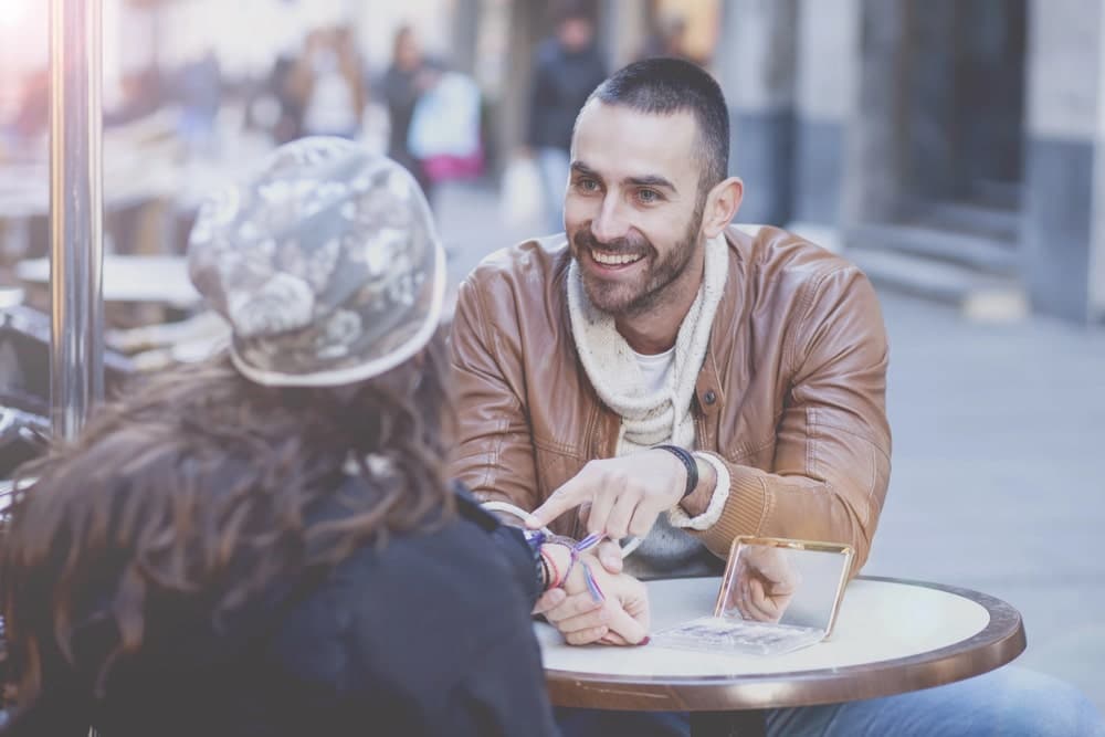 Image is of two adults sitting at an outdoor café having a friendly conversation, concept of dating relationships during divorce proceedings in Tennessee.