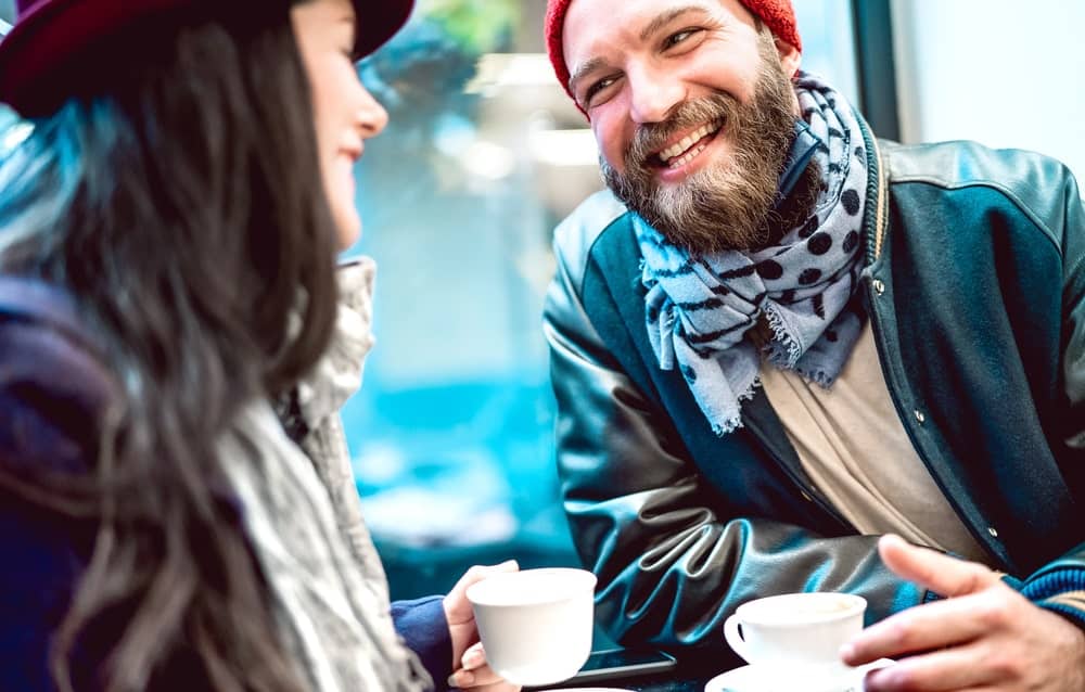 Image is of a couple smiling and talking over coffee indoors, concept of starting a new relationship during divorce proceedings in Tennessee.