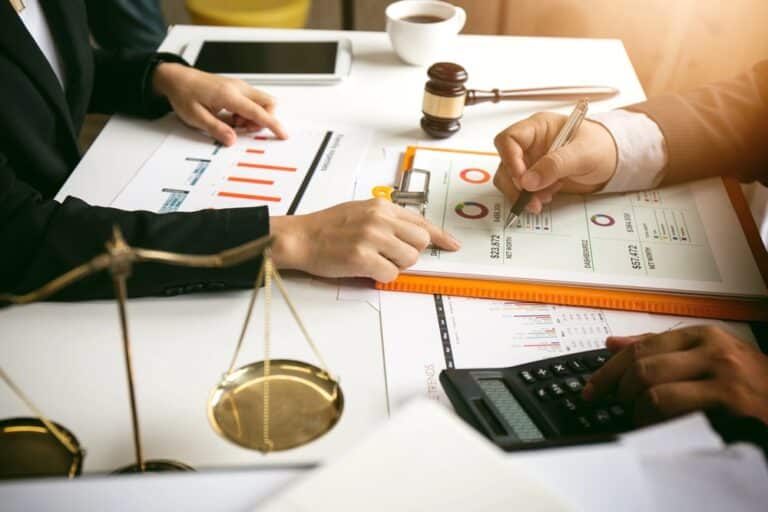 Image is of two attorneys reviewing financial reports and calculations together, illustrating legal and financial planning during a Tennessee divorce.