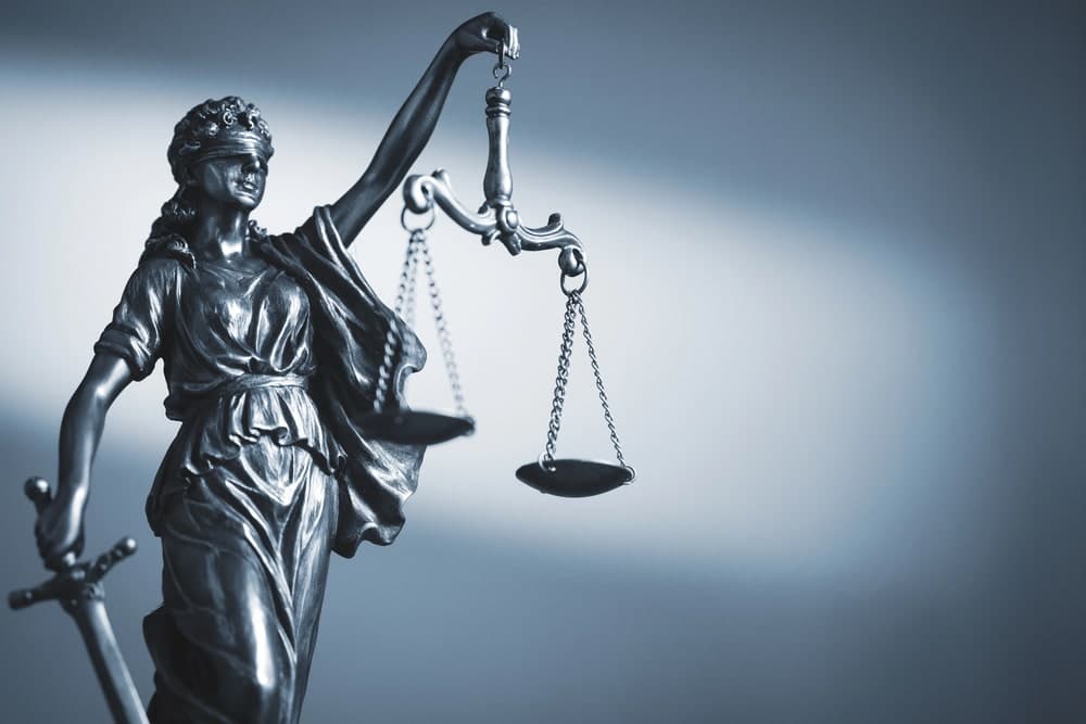 Image is of a Lady Justice statue holding balanced scales, representing how domestic violence impacts custody decisions during legal proceedings.