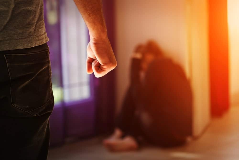 Image shows a man with a clenched fist standing over a frightened person on the floor, illustrating how incidents of abuse demonstrate the ways domestic violence impacts custody in Tennessee cases.