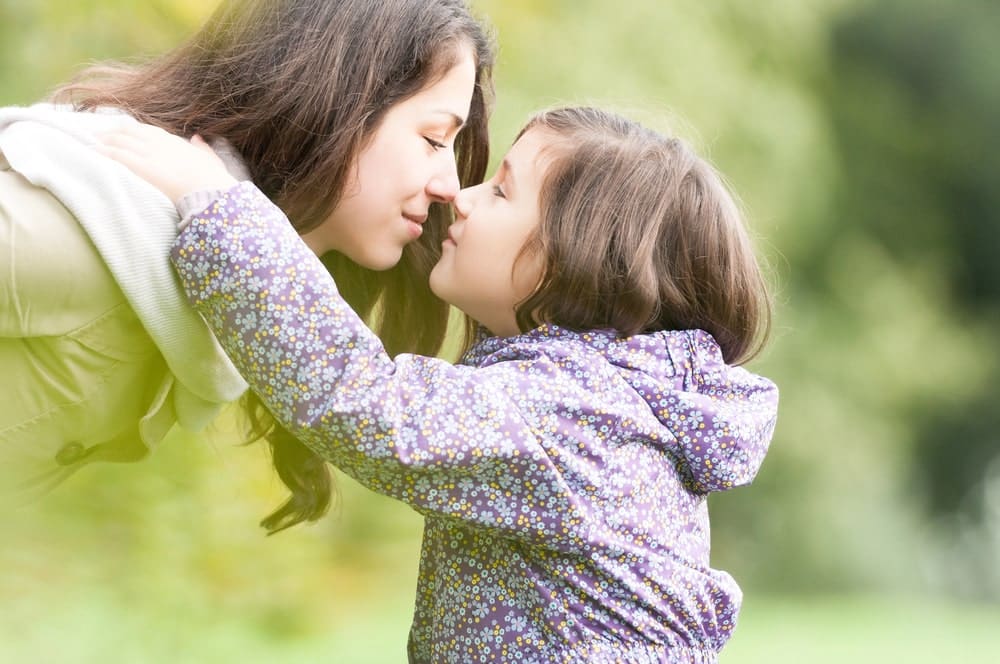 Image is of a mother and young child sharing a close, affectionate moment outdoors, representing parent child relationships evaluated in Tennessee custody hearings.