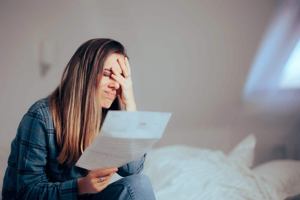 Image is of a woman reading financial paperwork at home, highlighting emotional stress and how divorce affects taxes after separation