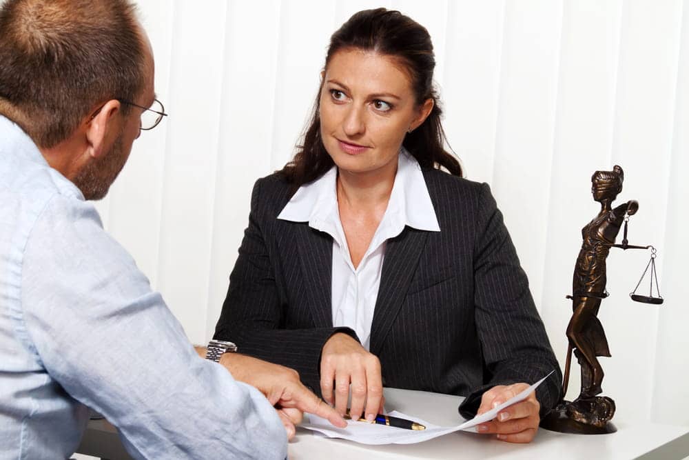 Image is of a lawyer reviewing paperwork with a client during a consultation, showing how divorce affects taxes in complex legal situations