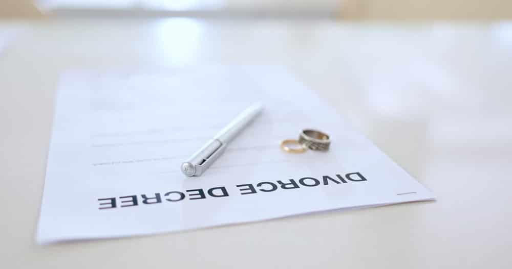 Image is of a signed divorce document with wedding rings and pen on table, concept of divorce decree in Tennessee