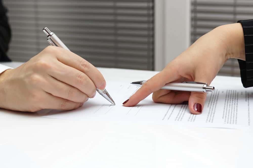 Image is of hands signing official legal paperwork with pen, concept of divorce decree in Tennessee