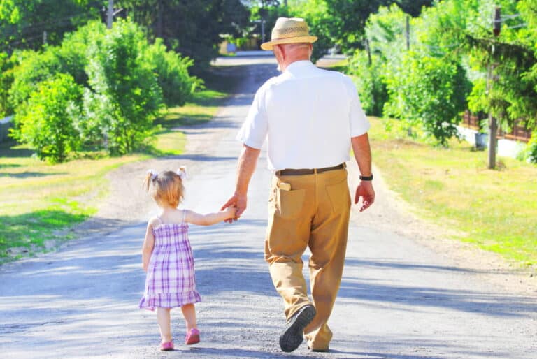 Image is of a grandparent walking hand in hand with a child, symbolizing long term care and emotional bonds in child custody cases.
