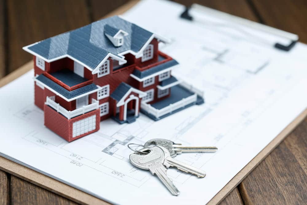 Image is of a model home and house keys placed on architectural plans, concept of divorce in Franklin involving real estate division.