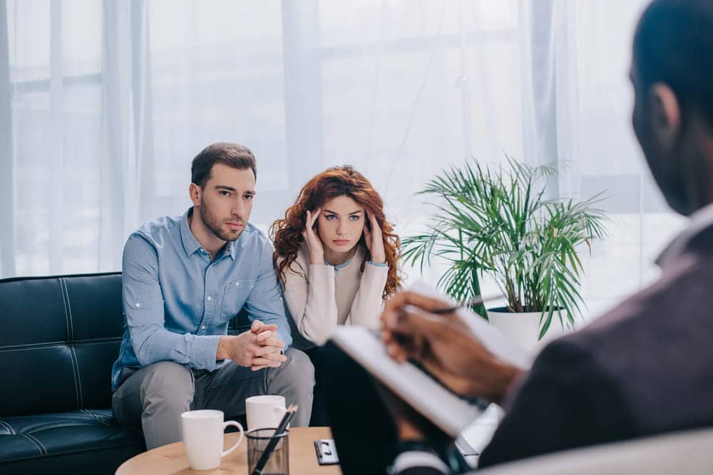Image is of a stressed couple speaking with a counselor, showing conflict relevant to divorce cases in Franklin