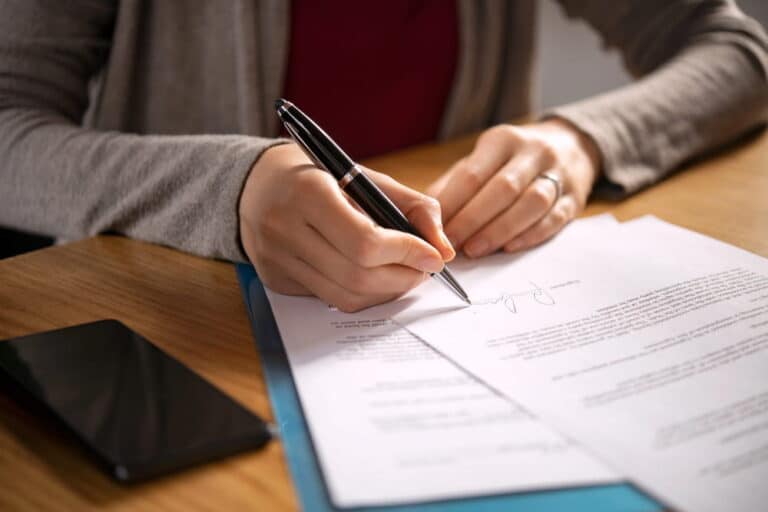 Image is of a parent signing legal paperwork, concept of filing custody orders in Tennessee through the court system.