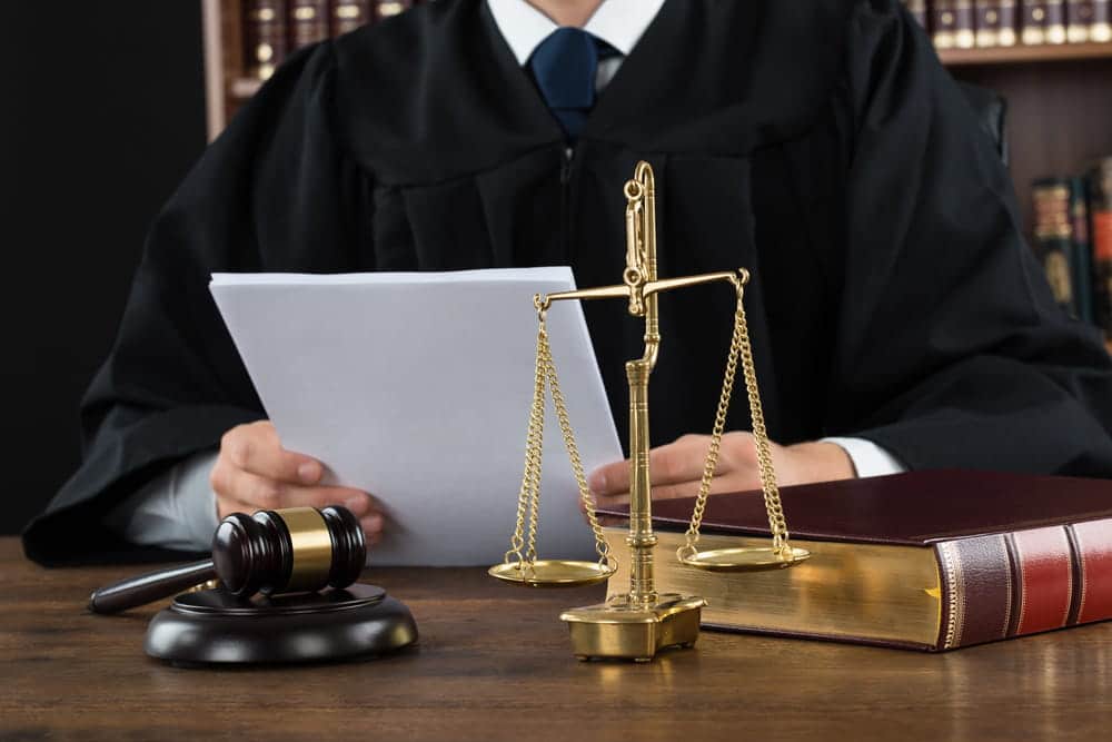 Image is of a judge reviewing legal documents with scales of justice and a gavel on the desk, concept of divorce in Franklin court proceedings.