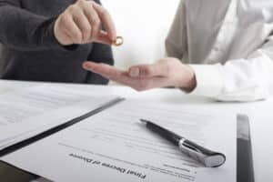 Image is of one person handing over a wedding ring across legal papers, concept of divorce in Franklin
