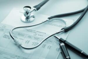 Image is of a stethoscope resting on a medical insurance document, representing divorce and health insurance coverage changes and medical billing concerns