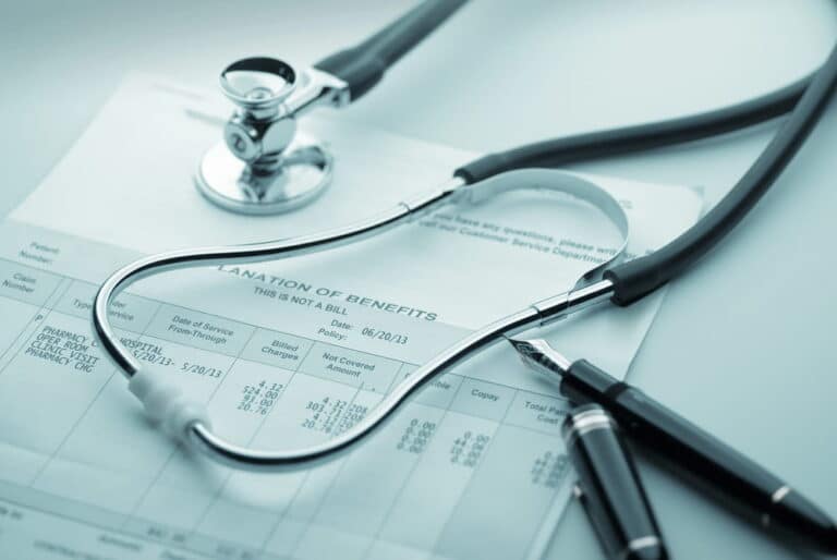 Image is of a stethoscope resting on a medical insurance document, representing divorce and health insurance coverage changes and medical billing concerns
