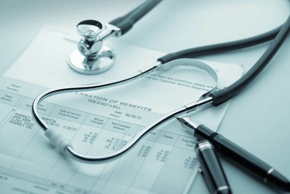 Image is of a stethoscope resting on a medical insurance document, representing divorce and health insurance coverage changes and medical billing concerns