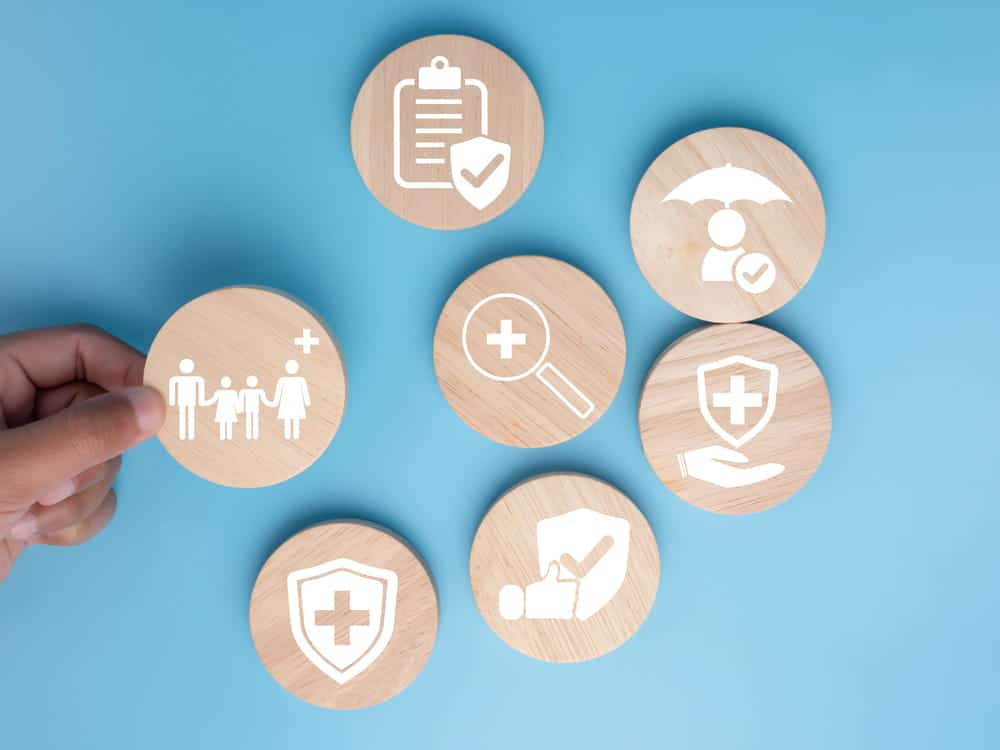 Image is of health and insurance icons on wooden discs, illustrating policy choices and planning during divorce and health insurance adjustments