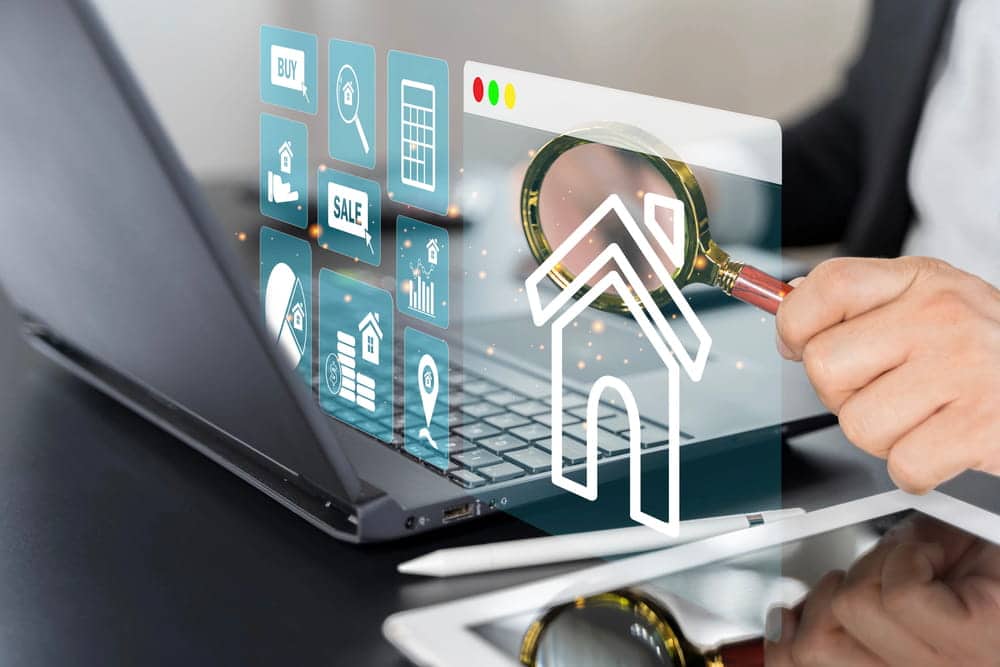 Image is of a magnifying glass over a laptop with property icons, representing investigation of high net worth divorce assets