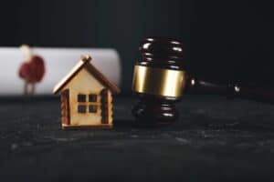 Image is of a judge’s gavel placed beside a small house model, illustrating property division in a high net worth divorce case