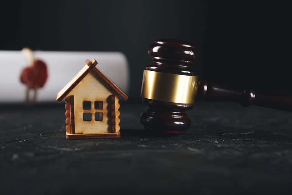 Image is of a judge’s gavel placed beside a small house model, illustrating property division in a high net worth divorce case