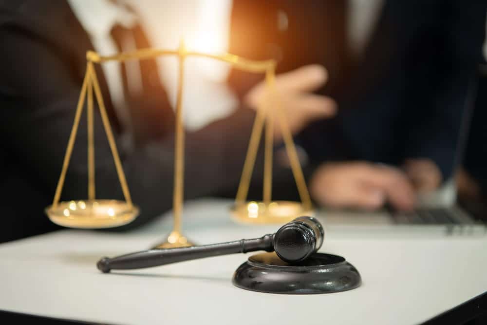 Image is of a gavel and balance scale on a desk during a legal discussion, concept of high net worth divorce asset division in court