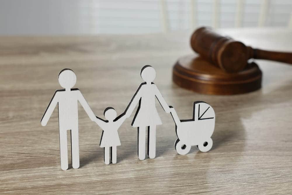 Image is of symbolic family figures beside a courtroom gavel during adoption proceedings, concept of Franklin adoption lawyer.