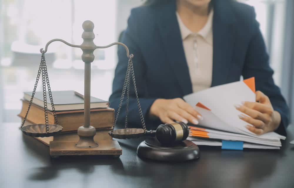 Image is of a family law attorney reviewing financial and court documents beside scales of justice, concept of Franklin child support lawyer handling legal support and payment disputes.