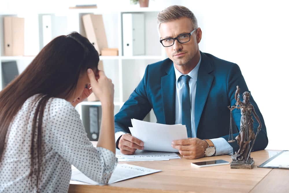 Image is of a woman discussing legal paperwork with an attorney during a divorce meeting, concept of a Franklin contested divorce lawyer guiding clients through contested family law matters.