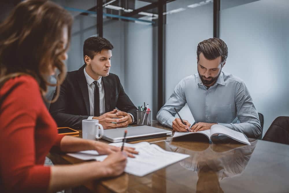 Image is of individuals reviewing legal documents during a settlement meeting, concept of a Franklin divorce lawyer assisting clients with divorce mediation preparation and negotiations.