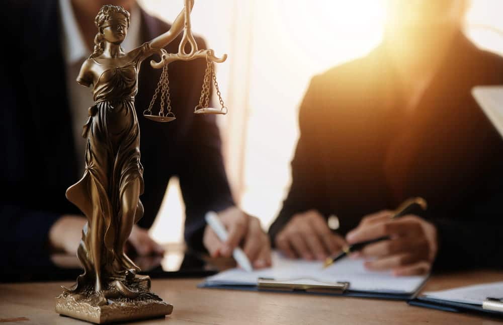 Image is of legal professionals discussing marital agreements beside scales of justice, concept of Franklin postnuptial agreement lawyer.