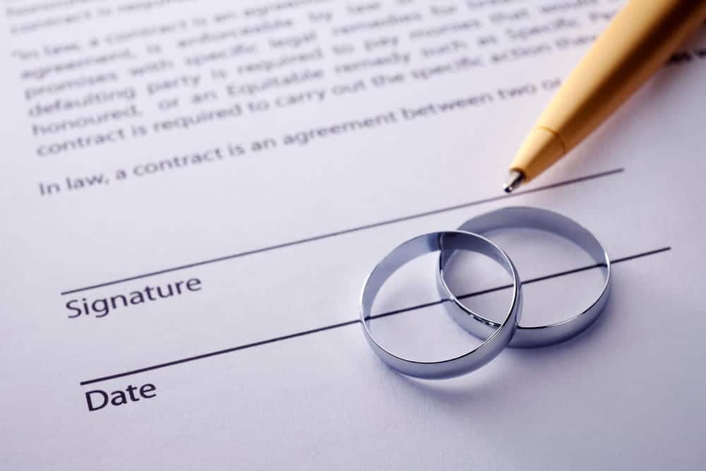 Image is of wedding rings placed on a legal agreement document during marital contract planning, concept of Franklin postnuptial agreement lawyer.