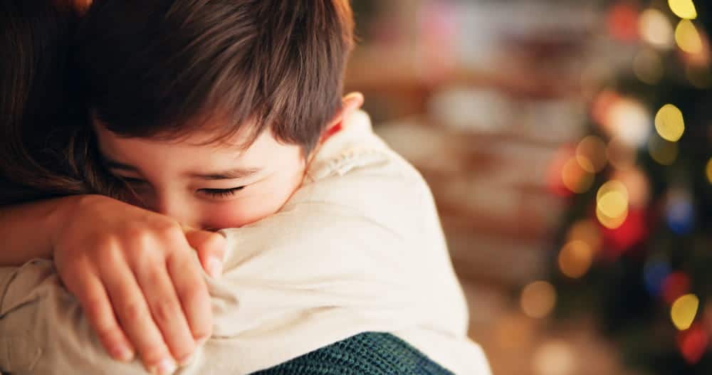 Image is of a child hugging a parent during the holiday season, concept of emotional stability for children after divorce in Franklin.