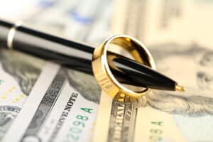 Image is of a wedding ring placed on cash with a pen, concept of Franklin divorce financial settlement and asset protection