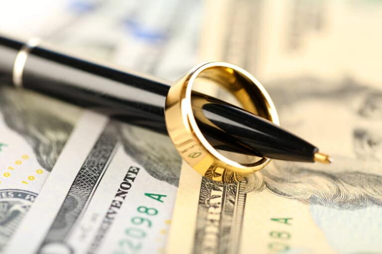 Image is of a wedding ring placed on cash with a pen, concept of Franklin divorce financial settlement and asset protection