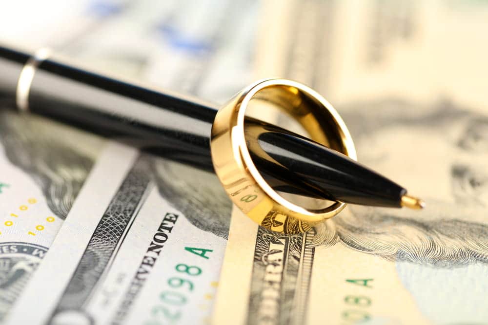 Image is of a wedding ring placed on cash with a pen, concept of Franklin divorce financial settlement and asset protection