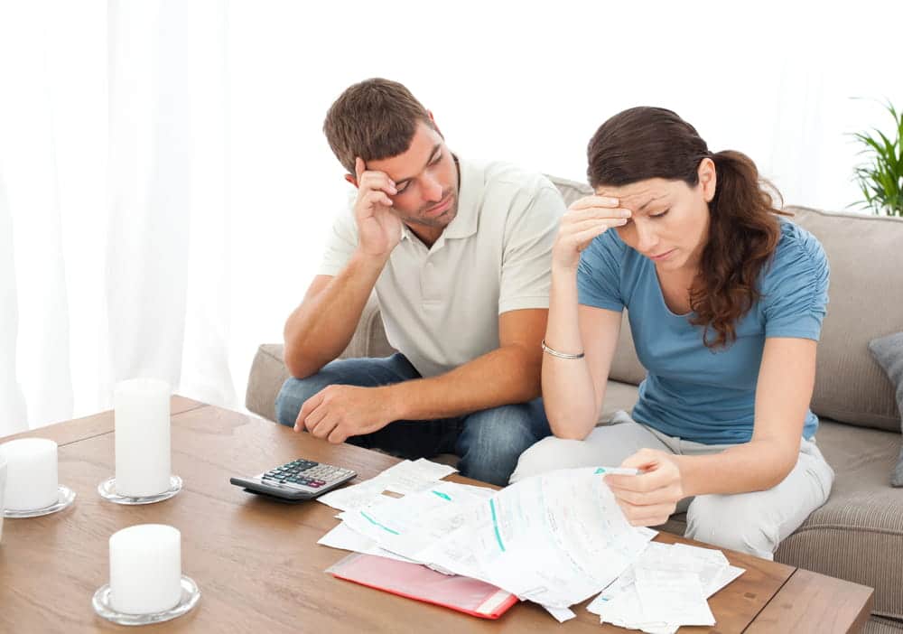 Image is of a divorcing couple reviewing bills, financial documents, and expenses at home, concept of divorce in Tennessee and debt division during divorce proceedings.