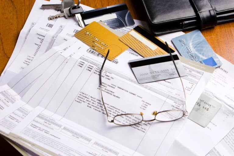 Image is of financial records, credit cards, and paperwork on a desk, concept of credit card debt allocation and marital finances after divorce.