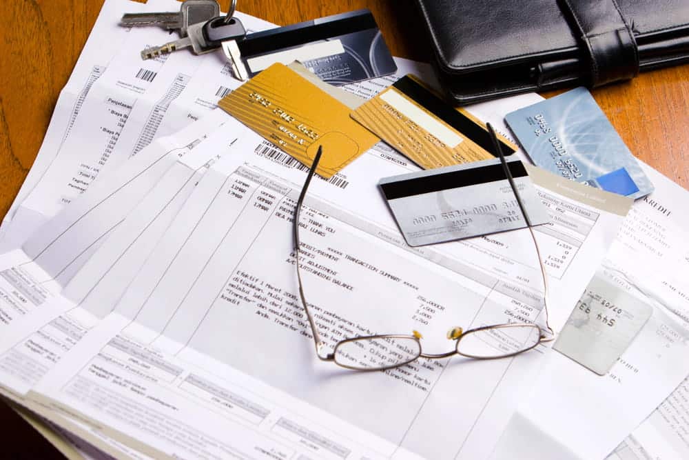 Image is of financial records, credit cards, and paperwork on a desk, concept of credit card debt allocation and marital finances after divorce.